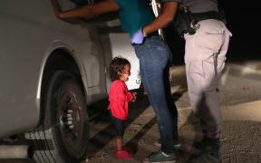 (FILES) In this file photo taken on June 11, 2018 a two-year-old Honduran asylum seeker cries as her mother is searched and detained near the U.S.-Mexico border in McAllen, Texas.