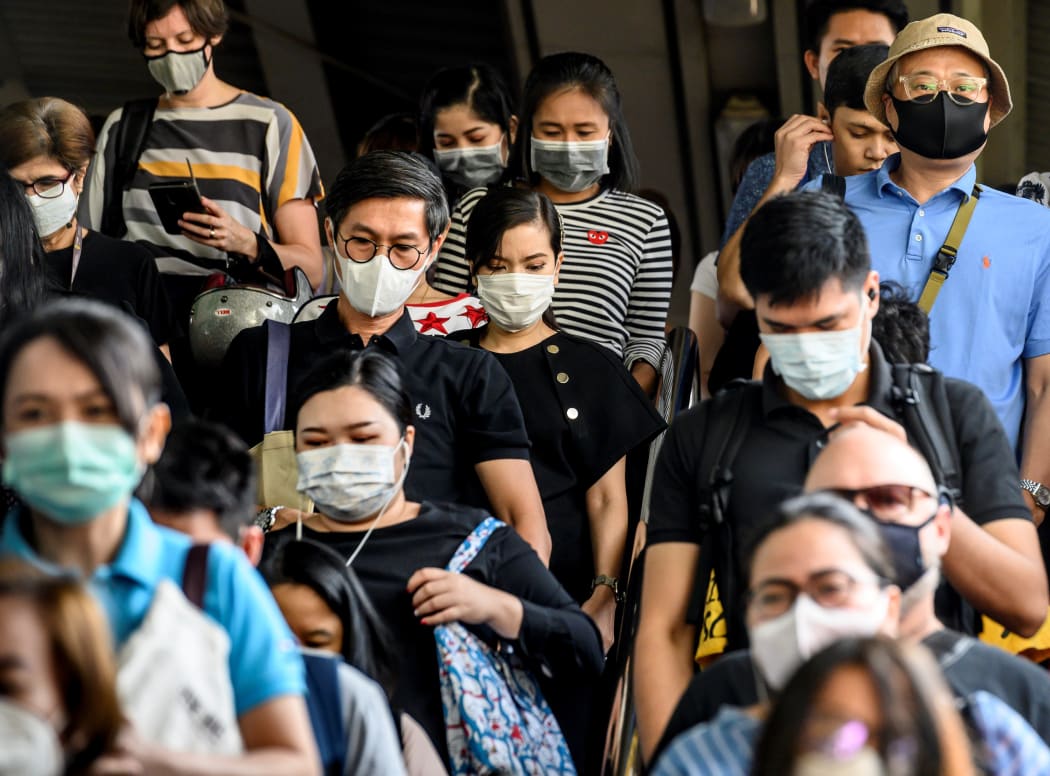 People wearing protective facemasks leave the city commuter train station in Bangkok.
