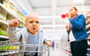 Unrecognizable young mother with her little baby boy at the supermarket, shopping.