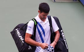 Novak Djokovic of Serbia walks off the court after being defaulted due to inadvertently striking a lineswoman with a ball.