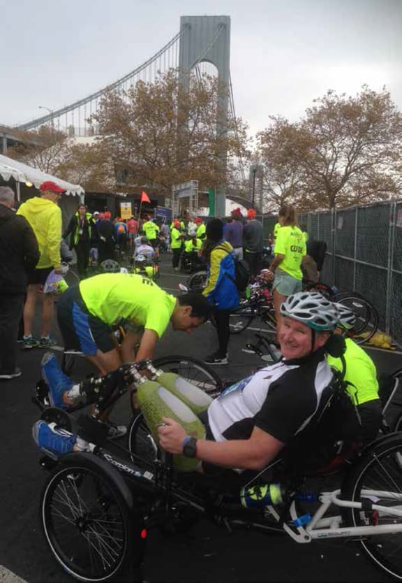 Ian Winson on his foot powered tricycle wheelchair surrounded by crowds a the New York Marathon