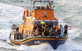 Migrants picked up at sea while attempting to cross the English Channel, are brought by a UK Royal National Lifeboat Institution (RNLI) lifeboat into the marina in Dover, southeast England. Six Afghan males died when a migrant boat heading to Britain sank in the Channel early on 12 August, 2023, French officials said, as a search continued to find those still missing.