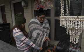 Karla Perez and Esperanza Gonzalez warm up by a barbecue grill during power outage caused by the winter storm on 16 February 2021 in Houston, Texas.
