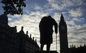 A statue of Winston Churchill is silhouetted by Big Ben and the Houses of Parliament in central London on the morning the Brexit results were announced.