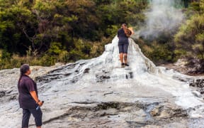 VALLEY OF GEYSERS ROTOROU, NEW ZEALAND - MARCH 24, 2018. The famous geyser of Lady Knox. The girl fills up in a geyser soap mixture to activate the eruption.