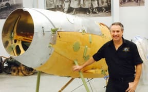 A photo of Gene DeMarco with a partly reconstructed Albatros DVa airplane