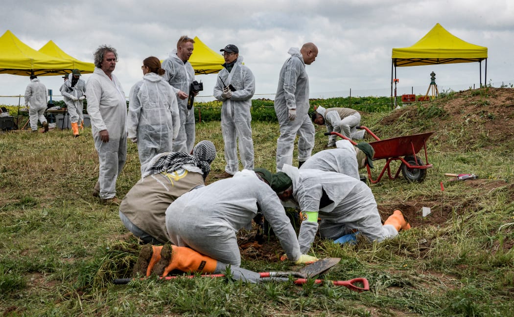 Forensic workers and experts inspect a zone during the 2019 exhumation of a mass-grave of hundreds of Yazidis killed by Islamic State (IS) group militants in Sinjar District in August 2014.