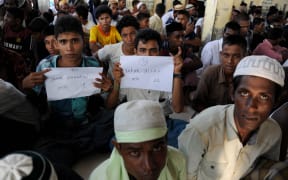 Rescued Myanmarese, part of a group of mostly Rohingyas from Myanmar and Bangladesh, prepare for a photographic identification procedure by an Indonesian immigration official in Aceh.
