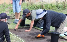 Whānau members dig out the marked excavation pit at Tikoraki point.