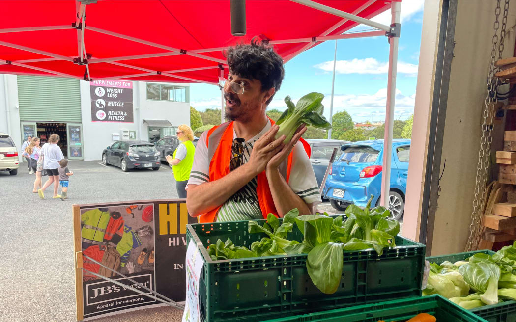 A volunteer holding bok choy at the Westgate market.