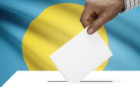 hand voting with Palau flag in background