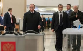 Russian President Vladimir Putin, foreground left, casts his vote at Polling Station No. 2151 at the Russian Academy of Sciences on Unified Election Day.
