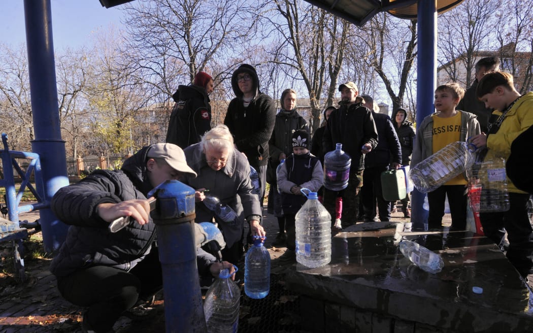 Kyiv residents fill plastic containers and bottles at a water pump in a park on 31 October 2022 after what Ukrainian officials called another 