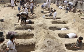 Yemenis dig graves for children, who where killed when their bus was hit during a Saudi-led coalition air strike, that targeted the Dahyan market the previous day in the Huthi rebels' stronghold province of Saada.