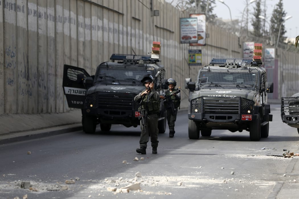 Israeli borderguards walk in front of military vehicles during clashes with Palestinian youth in the Palestinian village of al-Ram, between Jerusalem and Ramallah in the Israeli occupied West Bank, on October 22, 2015.