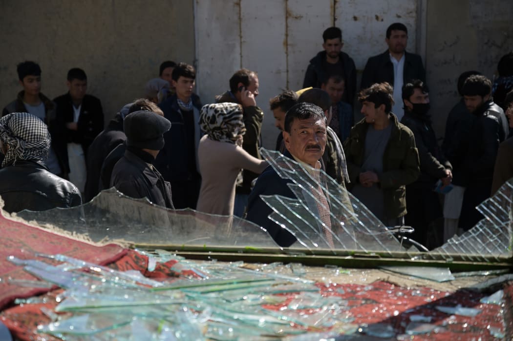 People walk past the site of a suicide car bombing; one of two Taliban attacks in Kabul on the same day.