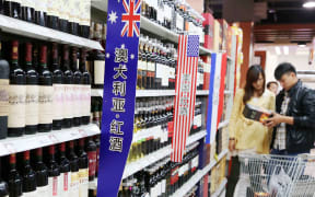 --FILE--Chinese customers shop for wine imported from Australia, the United States or France at a supermarket in Xuchang city, central China's Henan province, 17 October 2013.