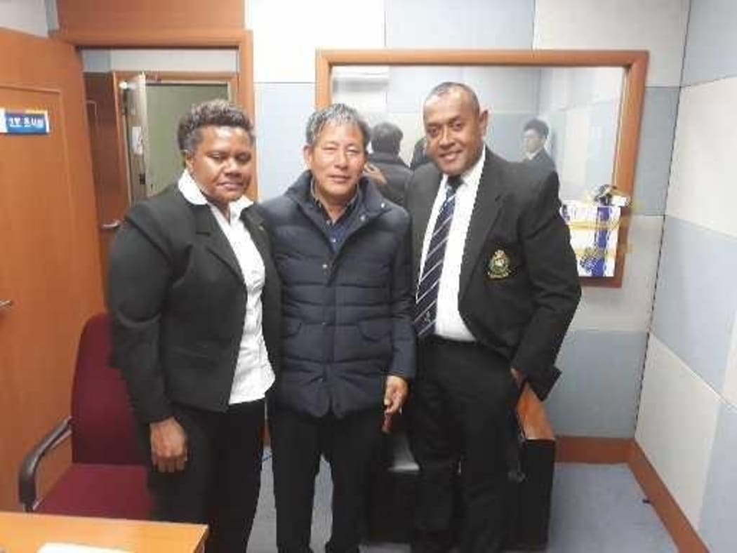 Former church member Yoon-jae Lee with two Fijian police officers