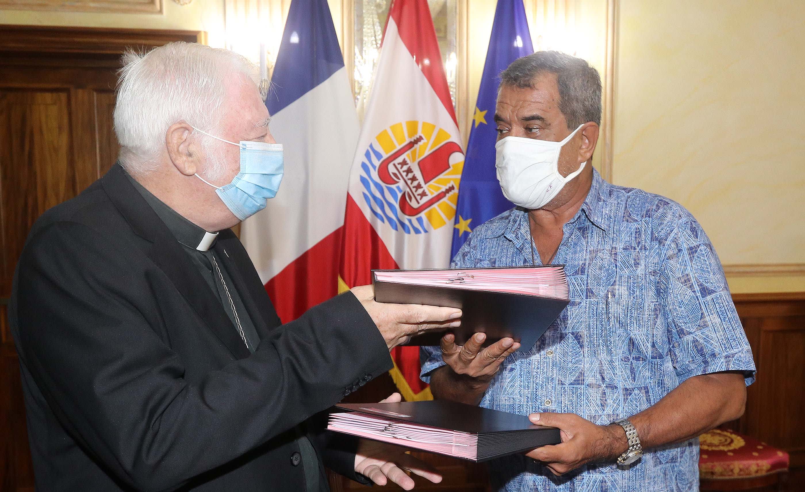 Monsignor Jean-Pierre Cottanceau and president Edouard Fritch swap lease agreements.