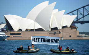 Members of Greenpeace hold up a sign  in front of the Opera House in Sydney on February 14, 2016.