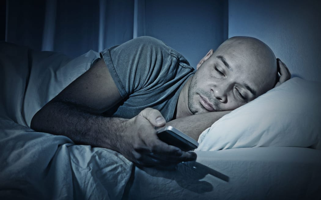 Sleeping man in bed with smartphone