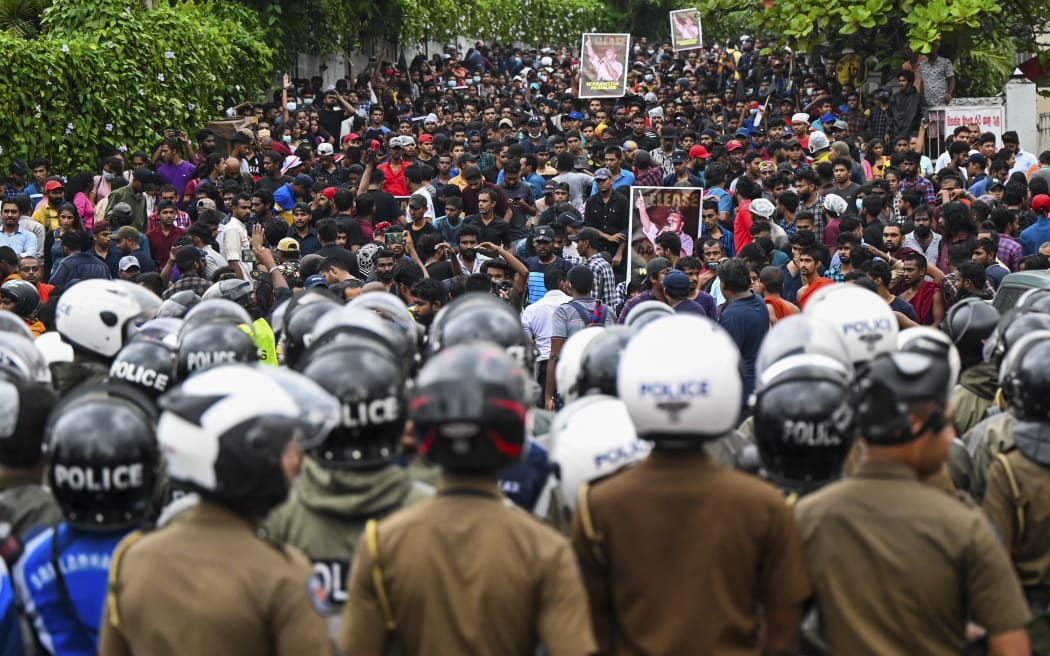 Protestocular, 18 Ekim 2022'de Colombo'da üniversite öğrencileri tarafından liderlerinin serbest bırakılmasını talep etmek için düzenlenen hükümet karşıtı bir gösteriye katılırken polisler nöbet tutuyor.