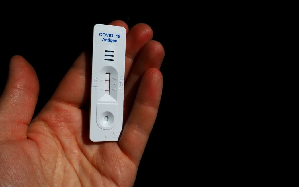 El resultado de la prueba para COVID-19 es positivo, infectado, utilizando equipo de prueba rápida.  Prueba de coronavirus sobre fondo de mano negra.  Copie el espacio.  Infección por enfermedad de coronavirus.  Dos tiras en la masa