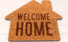Brown house icon shape coir doormat with text print Welcome Home on wooden floor. 3D illustration