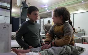 A Syrian boy talks to an injured girl as she lies on an operating bed in an emergency room in the rebel-held town of Douma in Syria's eastern Ghouta region on December 17.