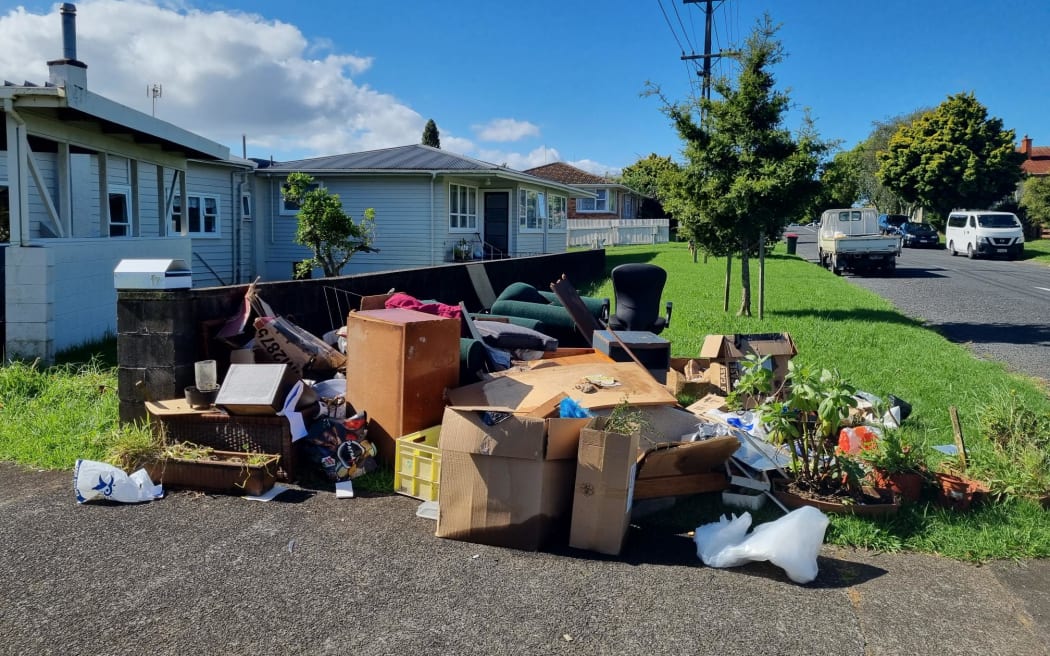 Flood-damaged furniture and  household items are piled on the roadside on a Mt Roskill street.