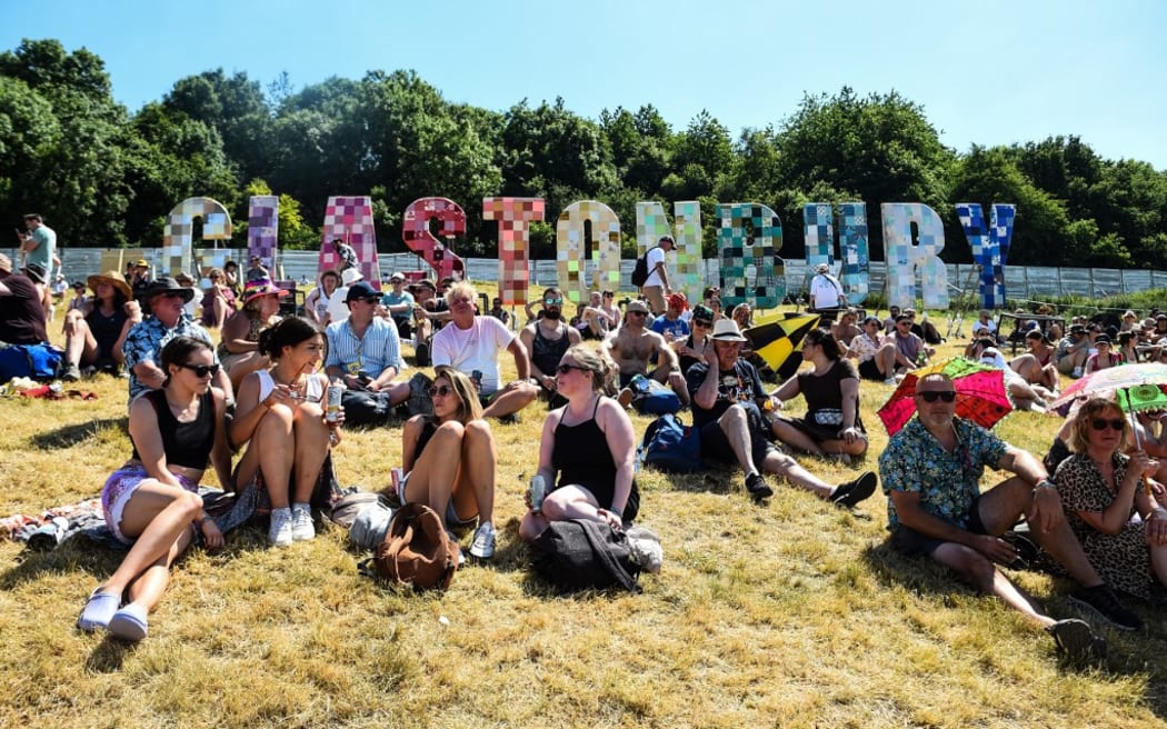 Festivalgoers enjoy the sun and warm weather as they attend the Glastonbury festival in the village of Pilton, in Somerset, South West England, on June 22, 2022. - More than 200,000 music fans and megastars Paul McCartney, Billie Eilish and Kendrick Lamar descend on the English countryside this week as Glastonbury Festival returns after a three-year hiatus. The festival takes place from June 22 to June 26, 2022. (Photo by ANDY BUCHANAN / AFP)