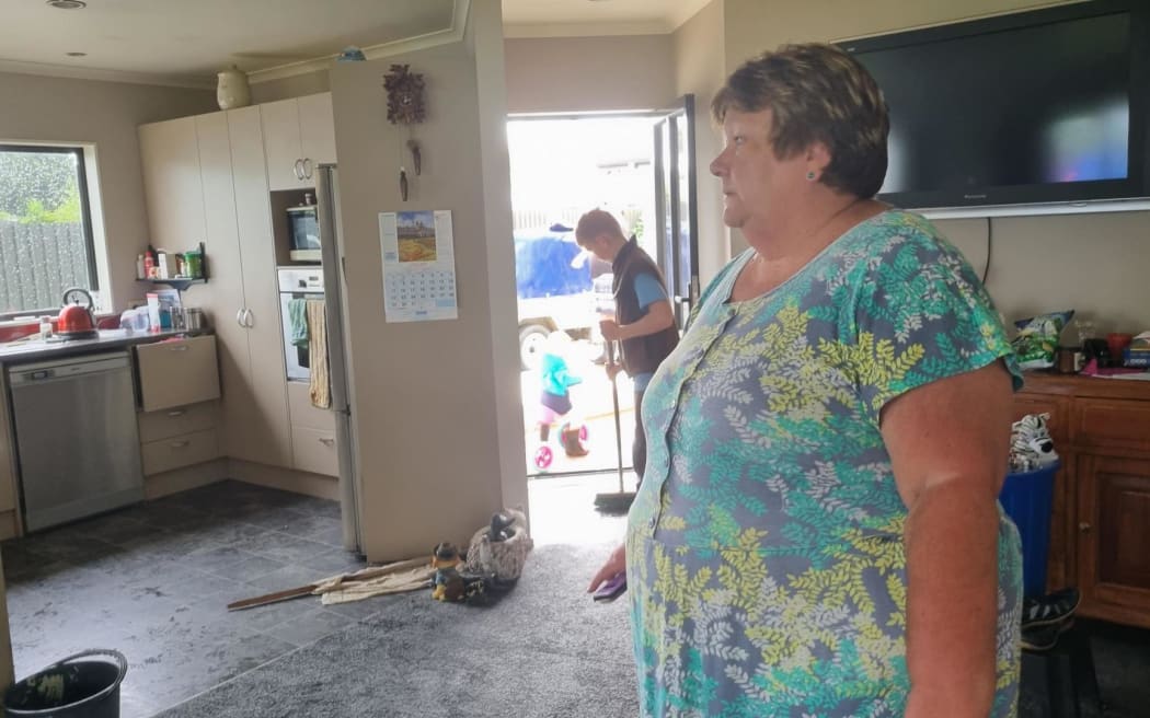 Raewyn Flexman surveys the damage of her Duke St home in Te Kuiti while family help with the clean up.