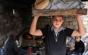 A young man carries a tray of freshly baked bread from a clay oven outside a home in Khan Yunis in the southern Gaza Strip on November 9, 2023 amid continuing battles between Israel and the Palestinian militant group Hamas. (Photo by MOHAMMED ABED / AFP)