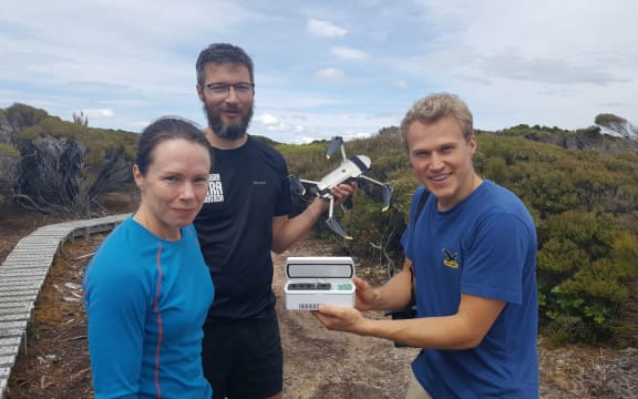 Flying kakapo sperm - a world first. DOC's Kakapo Recovery Team manager Deidre Vercoe with 'spermcopter' drone pilot Anton Marsden, and sperm expert Andreas Bublat holding a tiny vial of kakapo sperm.