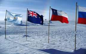 Flags of Argentina, New Zealand, Chile, and Russia at the ceremonial South Pole, with sundog. Amundsen-Scott South Pole Station, Jan. 14, 2010.