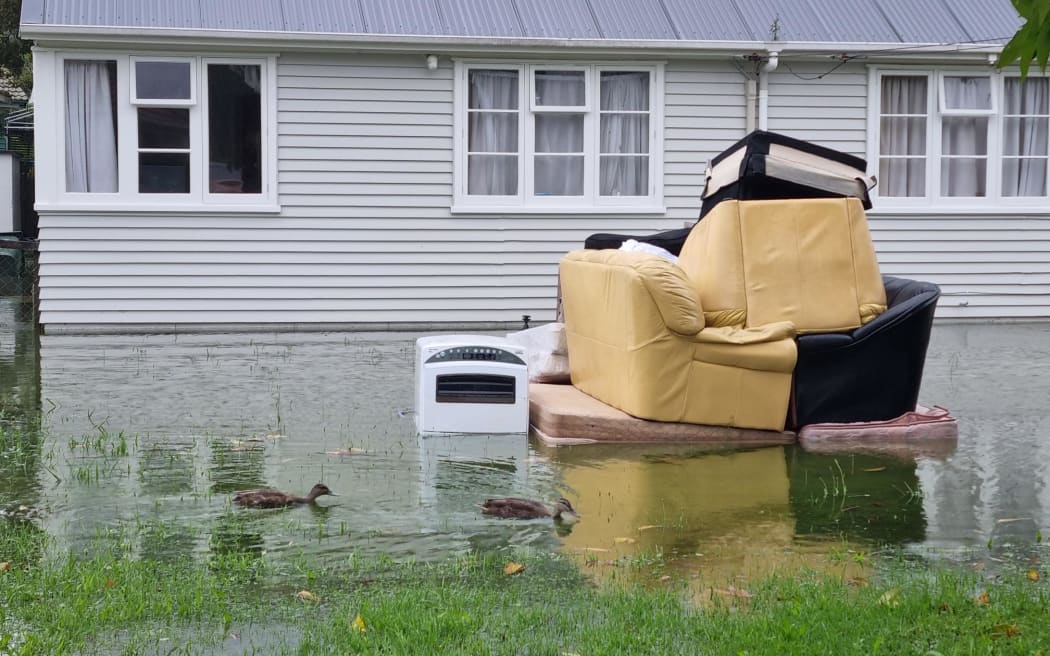 在罗斯基尔山湿透的草坪上，鸭子游过堆积如山的被洪水破坏的家具。