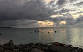 Funafuti lagoon, Tuvalu at sunset with a few  people in the water