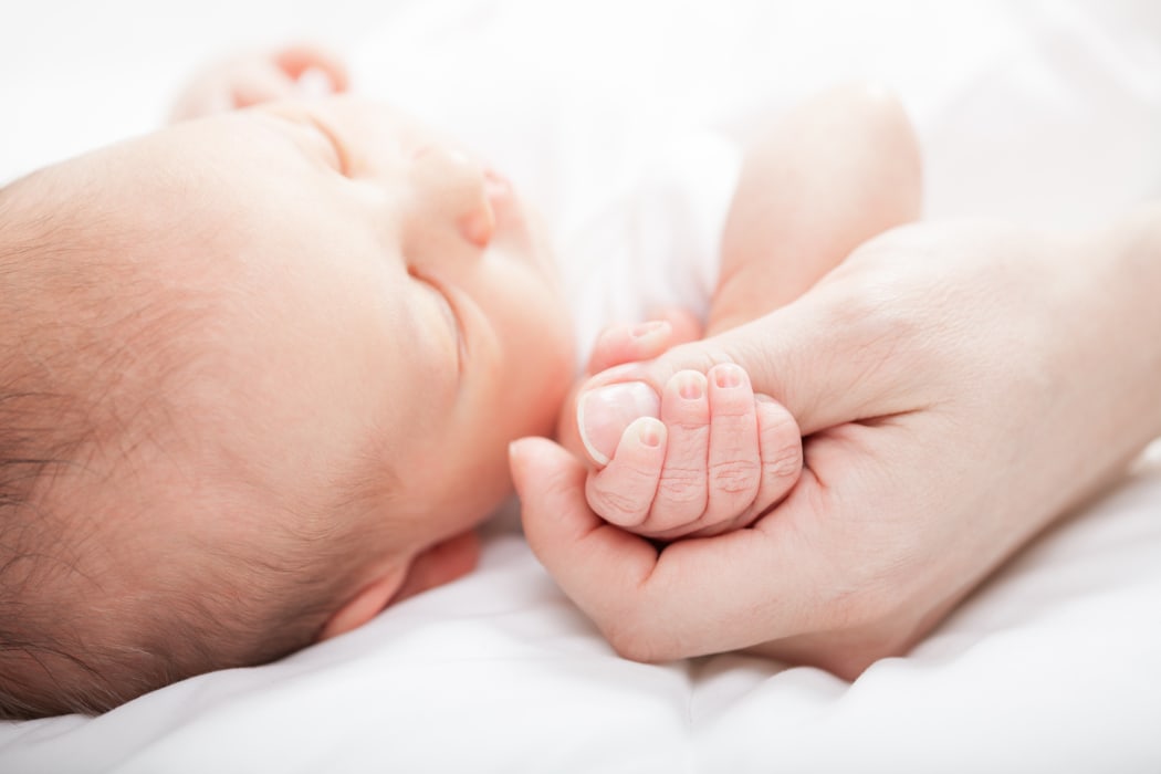 Newborn baby holding mother's thumb. (file pic)