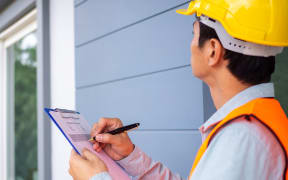 The inspector or engineer is checking the building structure and the requirements of the wall paint.