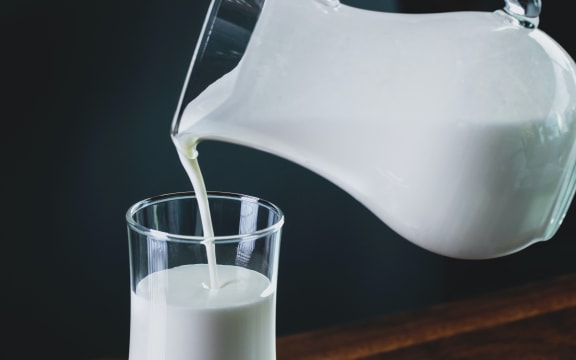 A jug of milk pours into a glass