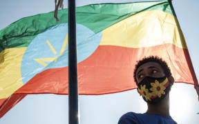A youngster stands below an Ethiopian national flag during a blood donation rally organised by the city administration of Addis Ababa on 12 November, 2020.