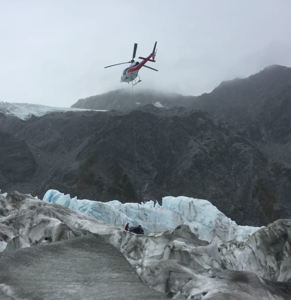 A mountaineer prepares helicopter wreckage for lifting from Fox Glacier.