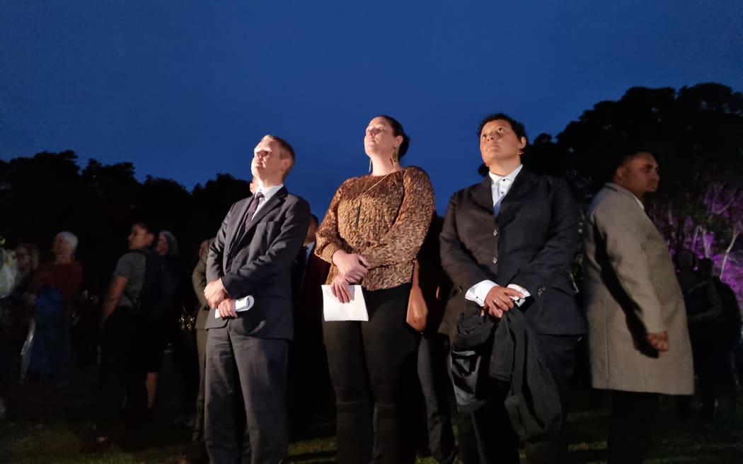 The crowd moves to the open field where the flag is being raised as dawn rises. Pictured: Prime Minister Chris Hipkins, Deputy Prime Minister Carmel Sepuloni and MP Kiri Allan.