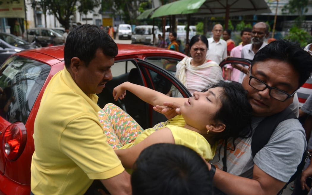 Indian hospital staff and bystanders attend to a resident who fainted as a tremor struck at Siliguri Hospital in Siliguri on May 12, 2015.