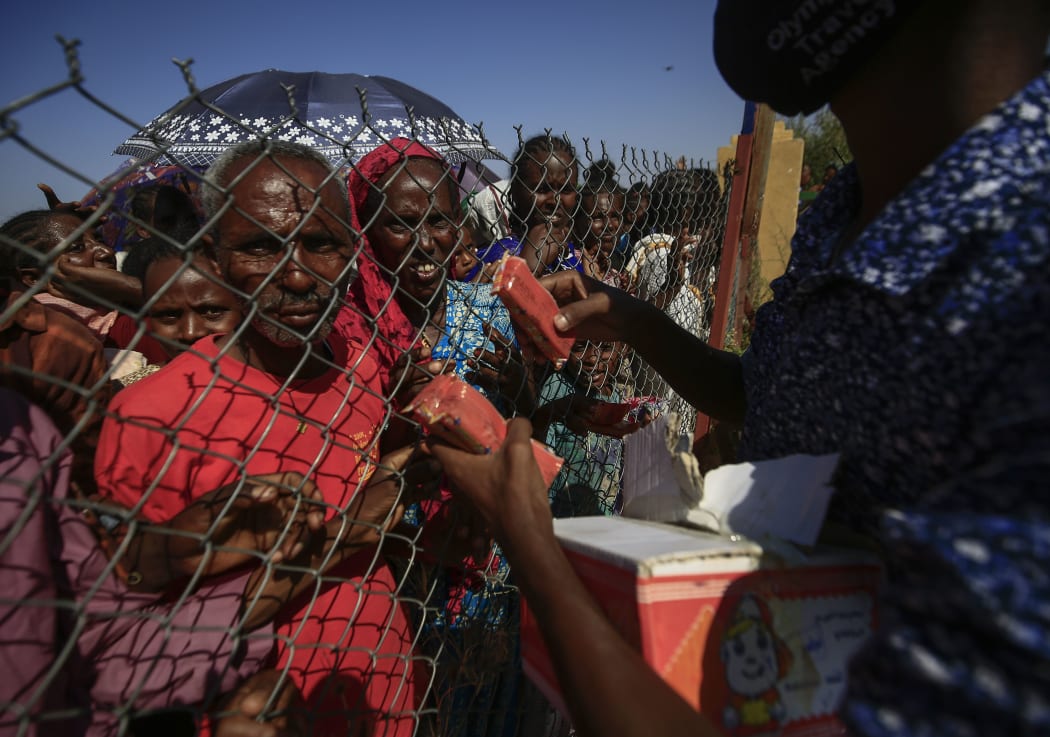 Ethiopian refugees who fled fighting in the Tigray Region receive snacks at the Village 8 border reception center in Sudan's eastern Gedaref State, on November 20, 2020.