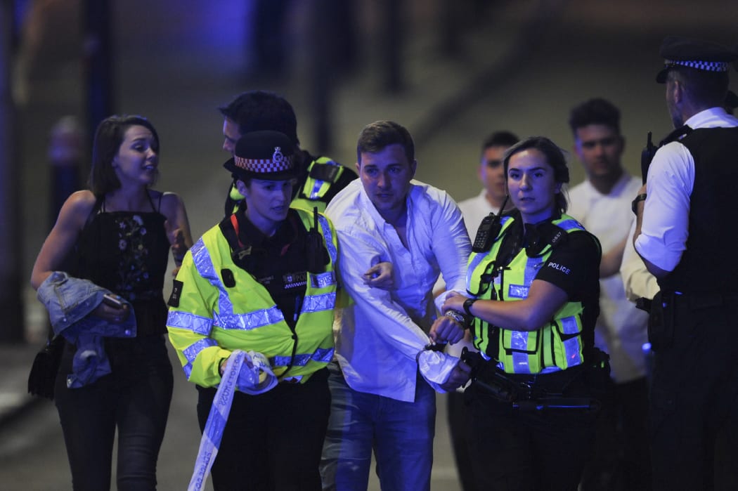 Police escort a member of public as they clear the scene of a terror attack on London Bridge.