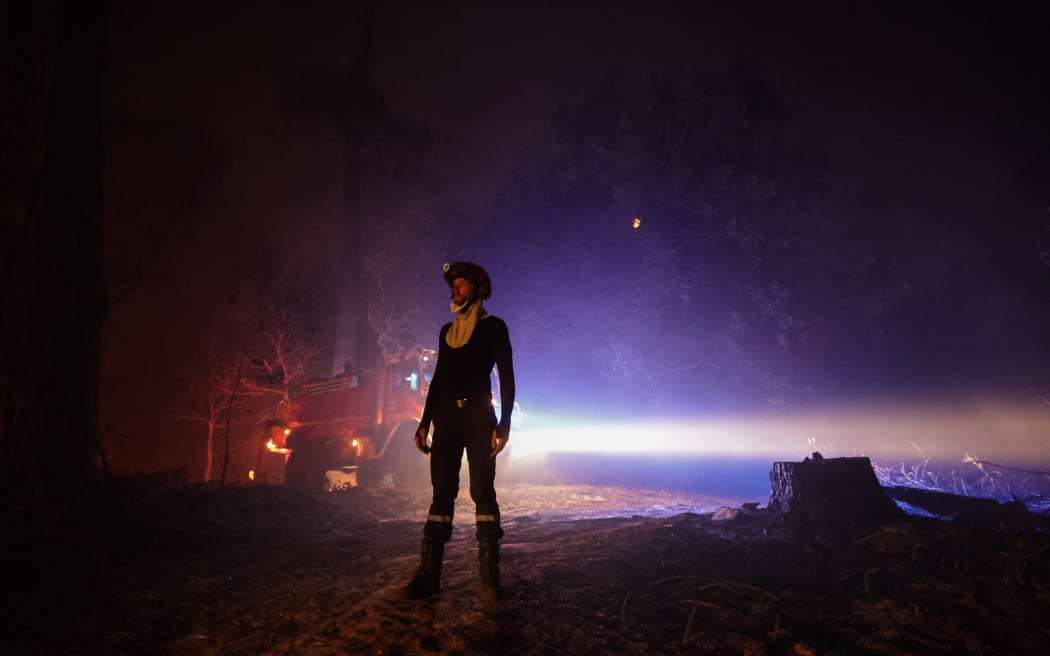 Un pompier se tient debout alors qu'un feu de forêt se propage dans la zone proche de la plage de Casaaux-Lac, près de La Teste-de-Buch, dans le sud-ouest de la France, le 15 juillet 2022. - Dans le contexte de chaleur intense dans la moitié sud du pays, les pompiers font toujours face à de violents feux de brousse en Gironde, où plus de 5 000 hectares ont été brûlés et plus de 10 000 personnes évacuées depuis le 12 juillet 2022, et se battent désormais 