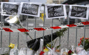 Flowers and signs that read, "Je suis Charlie", "I am police", "I am mourning", I am Jewish", near a kosher grocery store in Porte de Vincennes, eastern Paris.