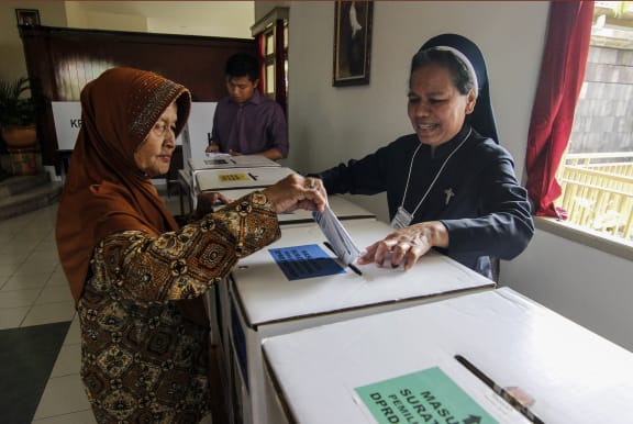 A Catholic nun assists an elderly Muslim woman to cast her ballot at a polling station at a convent in Yogyakarta, Indonesia, on 17 April, 2019.