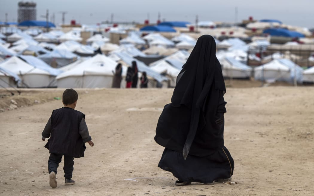 A displaced Syrian woman and a child walk toward tents at the Internally Displaced Persons (IDP) camp of al-Hol